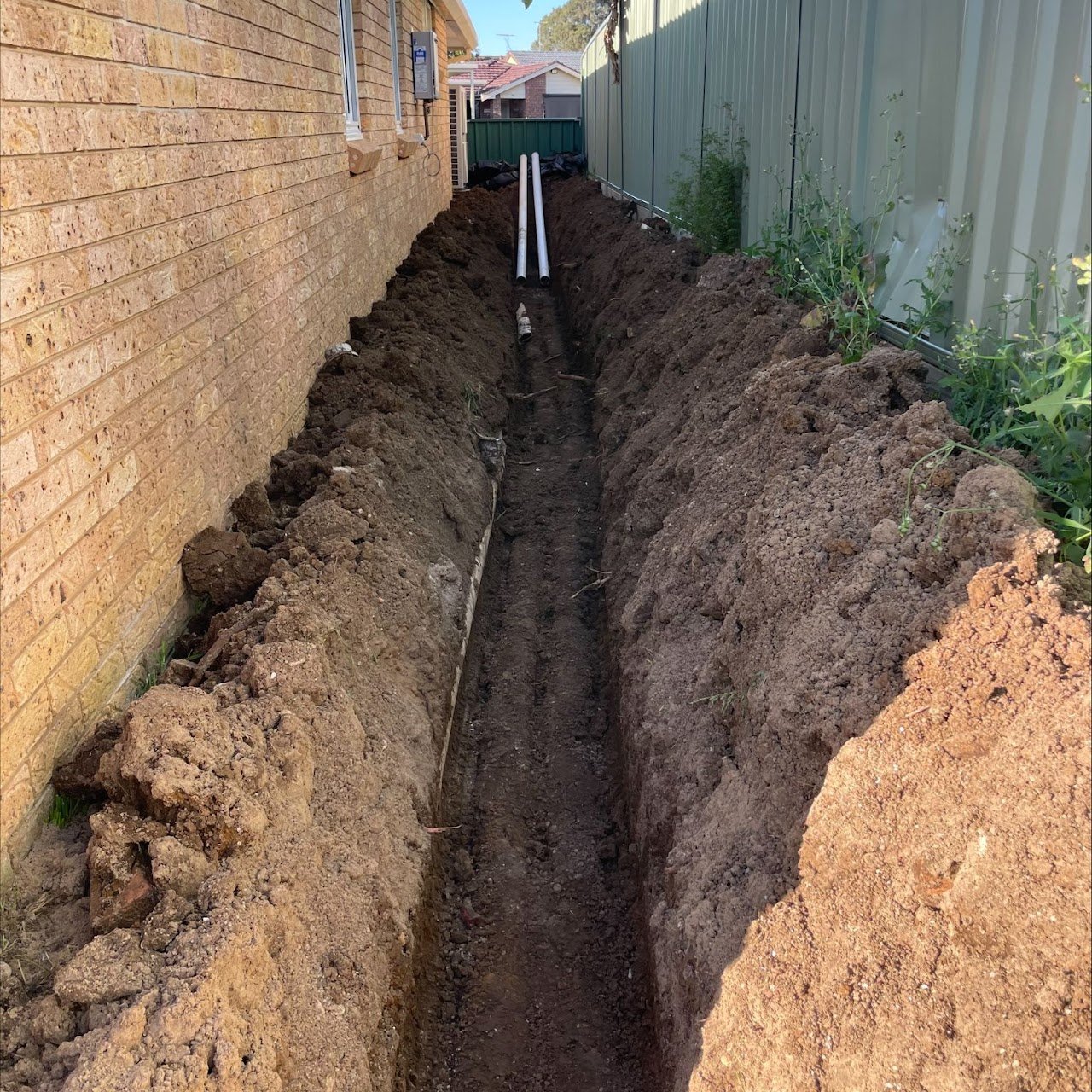Deep sewer trench replacement alongside brick house boundary