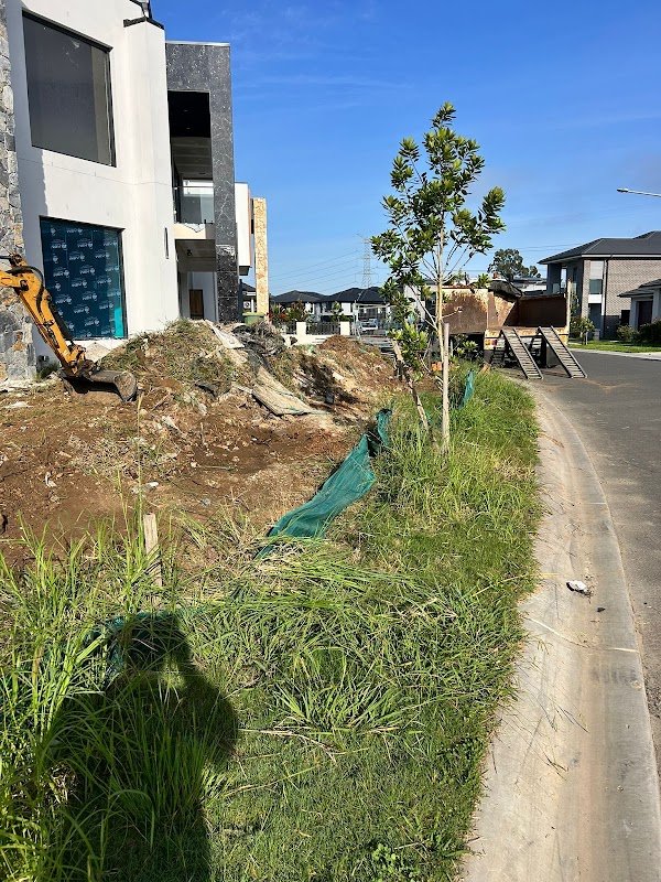 Excavator cutting into a spoil mound at a new estate home with tip truck waiting