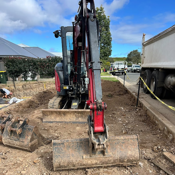 Excavator and operator trenching along a street frontage