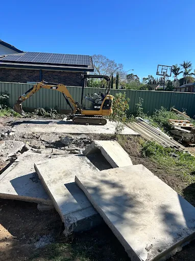 Compact machine clearing broken concrete from a demolition site