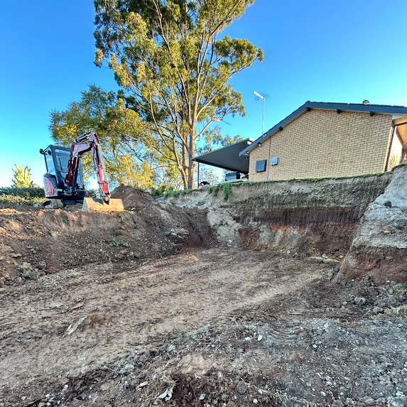 Excavator cutting a house pad into a sloped block