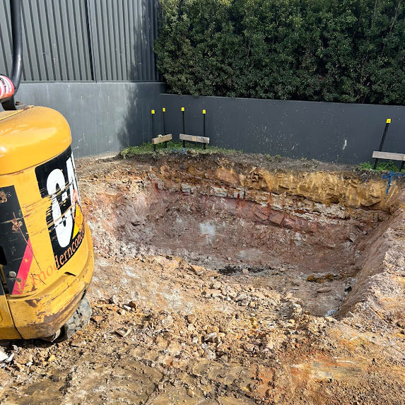 Bucket trimming clay along a boundary line