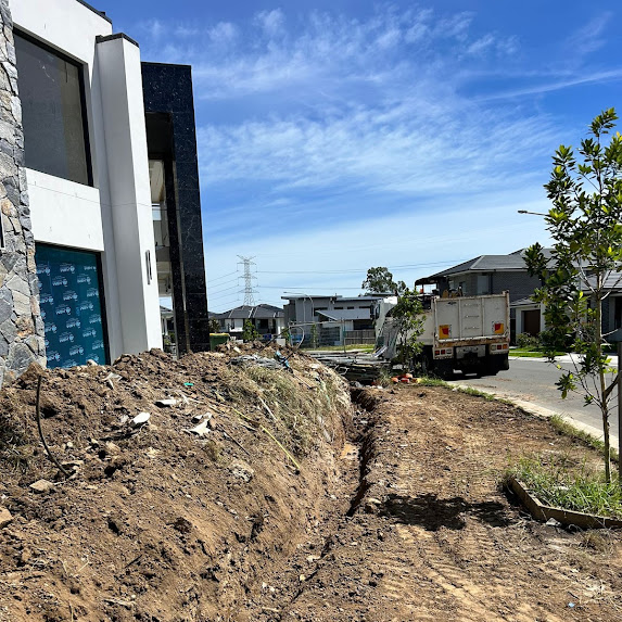 Trench dug across a slope ready for a retaining wall footing